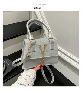 Detail of silver crossbody bag with crystal patchwork, V-logo, and gold tassel charm