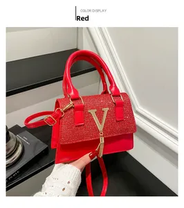 Detail of red luxury handbag with sequin flap and gold V hardware with tassel charm