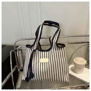 Detail of navy and white striped canvas tote bag with side pendant and dark handles