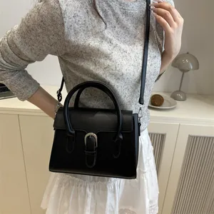 Minimalist black trapezoid handbag with silver buckle and detachable shoulder strap