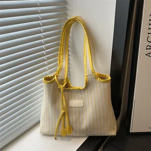 Minimalist yellow striped canvas tote bag with shoulder straps and hanging charm