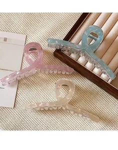 Close-up of three large pearlescent hair claws in pink, blue and cream white finishes