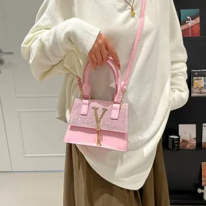 Elegant pink glitter crossbody bag with gold V-shaped hardware and metallic tassel