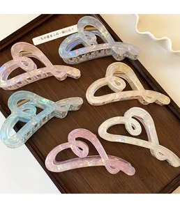 Close-up of five hollow heart-shaped hair claws with iridescent resin finish on a tray