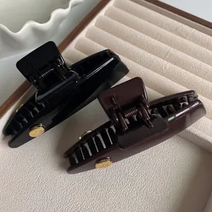 Elegant set of black and brown hair claws with golden metal accents on a velvet tray
