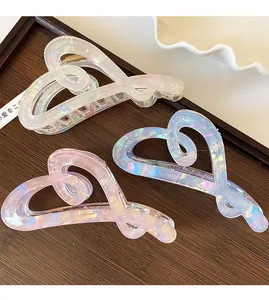 Detail of colorful iridescent heart hair claws in white blue and pink on wooden surface