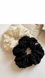 Detailed view of 19cm lace rose scrunchie in beige and black with fabric texture