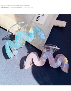 Detail of wave-shaped iridescent acrylic hair claws in pastel blue and pink with gold springs