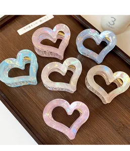 Detailed view of colorful heart-shaped hair claws on a wooden tray with pearl finish