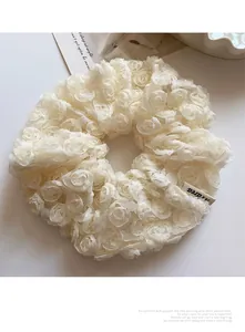 Detailed close-up of cream lace rose scrunchie with soft mesh texture and woven label
