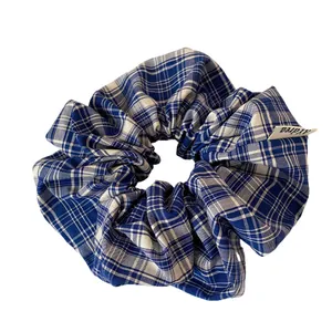 Stylish blue and white checkered fabric scrunchie with a minimalist textile brand tag