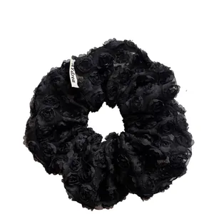 Elegant black lace scrunchie with 3D floral rose texture and brand label detail