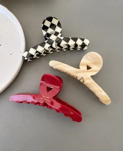 Three large tortoiseshell claw clips in checkerboard, marble, and red glossy finish
