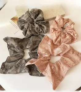 Close-up of four lace embroidered scrunchies in taupe and coral with floral patterns