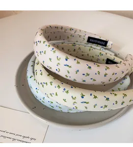 Set of three floral fabric wide headbands in pastel pink, beige and blue on a ceramic plate