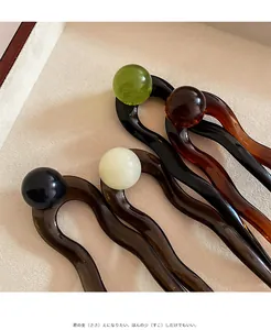 Detail of four multi-colored wavy U-shaped hairpins with smooth bead tops for buns