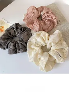 Detailed macro view of lace embroidered hair scrunchies in pink, gray, and beige silk