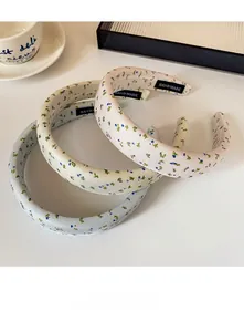 Detail view of floral sponge headbands in cream, blue, and pink with handmade labels