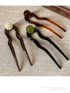 Close-up of wavy acetate U-shaped hair pins in amber, dark brown, and black colors
