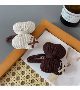 Close-up of cream and brown bow hair clips with Lucky embroidery on ribbon details