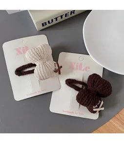 Close-up of beige and coffee bow hair clips with textured fabric and lucky ribbon details