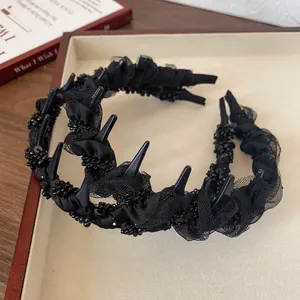 Gothic style black headband with mesh lace, spikes, and beaded details on a display box
