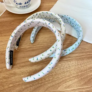Set of three handmade floral sponge headbands in cream pink and blue colors on a wooden table