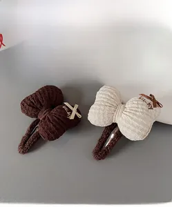 Detail of cream and brown seersucker bow hair clips with delicate lucky embroidery