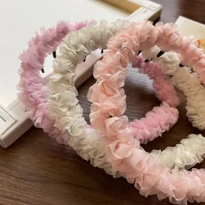Serre-têtes en tulle froncé rose et blanc avec dents sur une table en bois