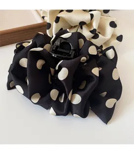 Detail of French large polka dot hair claws in black and cream satin fabric texture