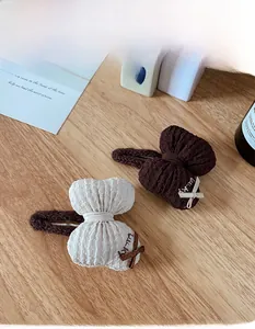 Detail of waffle textured bow hair clips in cream and brown with lucky embroidery