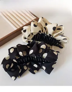 Close-up of black and beige polka dot fabric hair claws with elegant ruffled texture