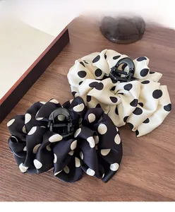 Detail view of large polka dot fabric claw clips with silk texture on wooden background