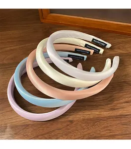 Détail de cinq serre-têtes rembourrés en satin pastel montrant les étiquettes faites main