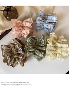 Dettaglio di elastici per capelli oversize colorati con ricami floreali in pizzo bianco