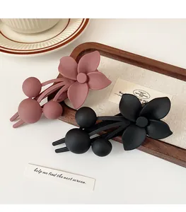 Close-up of matte Morandi flower hair clips in purple and black on a wooden tray
