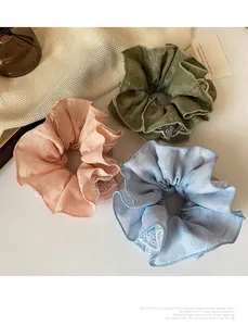 Dettaglio di elastici scrunchie rosa, verdi e blu con trama a pieghe e bordi in pizzo