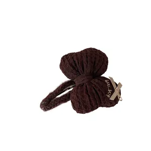 Brown waffle-textured bow hair clip with golden Lucky embroidery on a white background