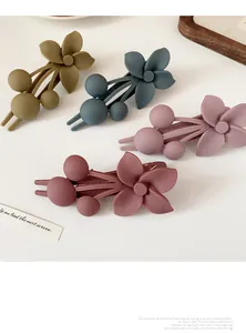 Detailed macro view of four matte floral hair clips in Morandi colors with ball accents