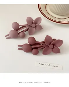 Close-up of two matte dusty rose flower hair clips on a clean minimalist background