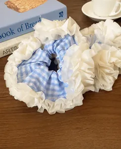 Close-up of blue plaid and white organza layered scrunchies on a wooden table