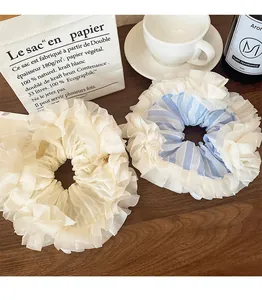 Detail shot of blue striped and beige lace scrunchies on a rustic wooden table surface
