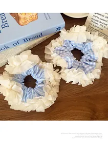 Detailed close-up of blue plaid and striped scrunchies with white lace on wood