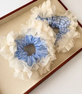 Close-up of blue plaid and striped scrunchies with white lace edges in a tray