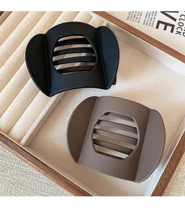 Detail of matte-finish rectangular hair clips in black and taupe on a velvet jewelry tray