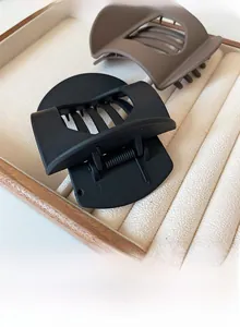 Detail of matte hair clips in black and coffee brown on a velvet display tray