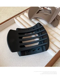 Detail view of large matte black and brown square hair claws on a jewelry display tray