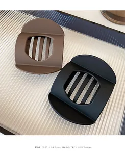 Detail of matte brown and black geometric hair clips with vertical hollow lattice design