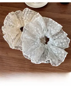 Detailed view of large floral lace scrunchies in cream and white organza fabric