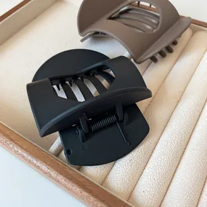 Minimalist matte hair claws in black and coffee brown colors on a soft velvet display tray